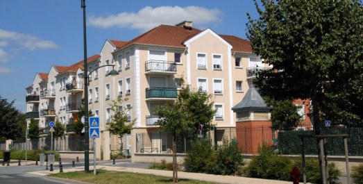 Résidence d’immeubles modernes avec balcons, toits en tuiles rouges et rue résidentielle arborée